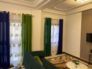 sala de estar con cortinas verdes y sofá en STEPHEN Meuble, en Yaoundé