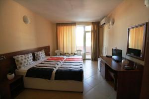 a bedroom with a bed and a desk and a television at Hotel Marant in Sozopol