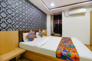 a bedroom with a bed and a wall at FabHotel Surbhi in Bhopal
