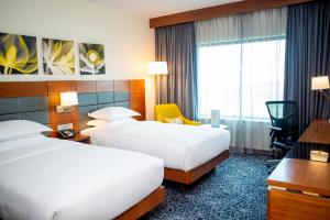 a hotel room with two beds and a desk at Hilton Garden Inn Nairobi Airport in Nairobi