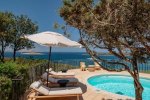 a pool with two lounge chairs and an umbrella at Hotel Pitrizza, Costa Smeralda in Porto Cervo