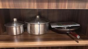 two metal pots on a wooden shelf with a scale at منازل بريدة للشقق المفروشة in Buraydah