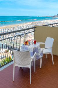 een tafel en stoelen op een balkon met uitzicht op het strand bij Hotel Belsoggiorno in Cattolica