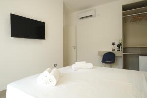 Un dormitorio con una cama blanca con toallas. en Marephis Rooms - Alghero, en Alghero