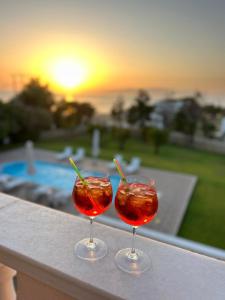 two cocktails sitting on a ledge with the sunset in the background at Eglina Celeste Villa in Minia