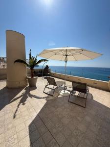 a patio with two chairs and an umbrella and the ocean at CasaForno1638 in Tropea