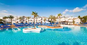 a large swimming pool with blue chairs and palm trees at Globales Bouganvilla in Sa Coma