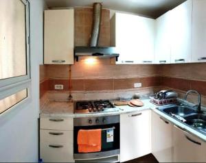 a kitchen with white cabinets and a stove and a sink at Location Estivale Hammamet in Bin Rhilouf