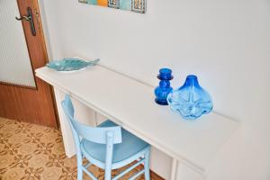 een witte tafel met een blauwe vaas en een blauwe stoel bij Cosentino apartment in Marzamemi