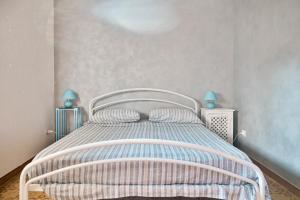 een slaapkamer met een wit bed met blauwe lampen bij Cosentino apartment in Marzamemi