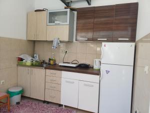 a kitchen with a white refrigerator and wooden cabinets at Tina Rooms in Ulcinj