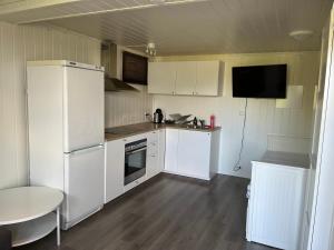 a kitchen with white cabinets and a white refrigerator at Liten,koselig studieleilighet i rolige omgivelser in Kristiansand