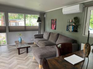 a living room with a couch and a table at Chalet Bosgeluk in Hoenderloo