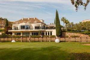 a large white house with a green yard at Luxurious frontline golf apartment in Elviria in Marbella