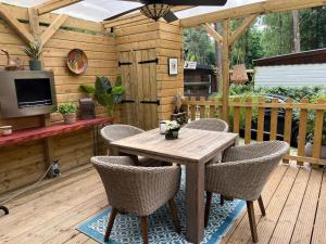 a wooden table and chairs on a wooden deck at Chalet Bosgeluk in Hoenderloo