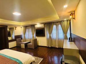 a hotel room with a bed and a television at President Boutique Hotel in Pashupatināth