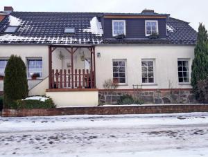 ein weißes Haus mit einem Holztor im Schnee in der Unterkunft Ferienwohnung mit großem Balkon in Bömitz in Bömitz + 19 Fotos