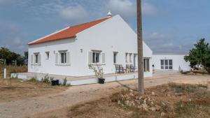 a white building with a red roof on a dirt road at Quinta Madrugada Burgau in Luz