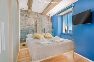 a bedroom with a bed with blue walls and a flat screen tv at Nidoo TerreMarine in Riomaggiore