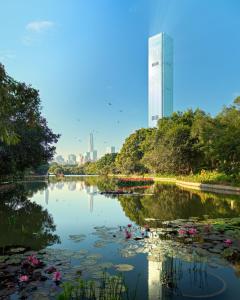 深圳Mandarin Oriental, Shenzhen的公园内的一个池塘,有一座建筑的背景
