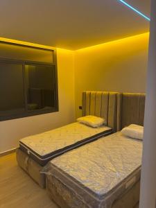 two twin beds in a room with yellow walls at Luxe Appartement Haut Standing Nador Lagoon Rif in Nador