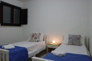 zwei Betten in einem Zimmer mit einer Lampe auf einem Tisch in der Unterkunft Casa Maria in Santa Cesarea Terme