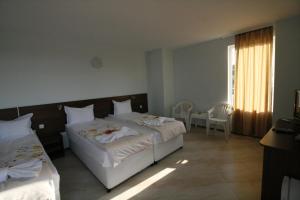 a bedroom with two beds and a table and a window at Hotel Marant in Sozopol