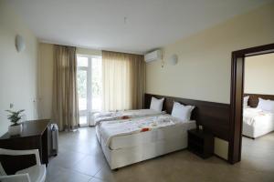 a hotel room with two beds and a desk at Hotel Marant in Sozopol