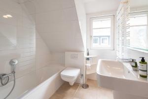 a white bathroom with a tub and a toilet and a sink at Haus Gorch Fock Strasse in Westerland +28 photos