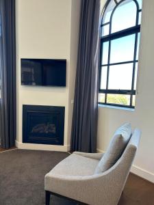 a living room with a chair and a fireplace at THE DEVLIN APARTMENTS 2 Bedroom Apartment near GMHBA stadium in Geelong - 108 in Geelong