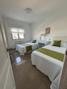 a bedroom with two beds and a table and two windows at Chancelas b in Combarro