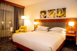 a hotel room with a large bed and a yellow chair at Hilton Garden Inn Nairobi Airport in Nairobi