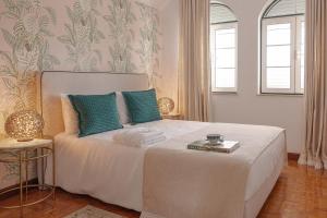 a bedroom with a large white bed with blue pillows at Porta do Jardim in São Pedro do Sul +6 photos