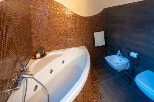 a bathroom with a white tub and a toilet at Villa DAutore in Alba
