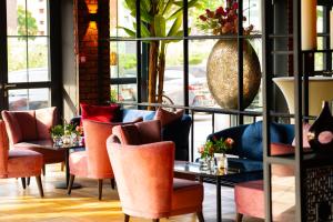 a restaurant with orange chairs and tables and a large window at Twins Hotel in Duisburg