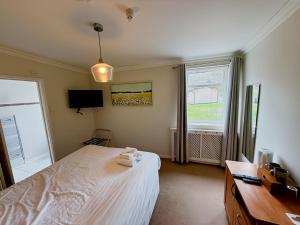a bedroom with a bed and a desk and a window at The Coach House in Otterburn