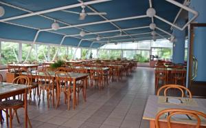a restaurant with wooden tables and chairs and blue ceilings at Hotel Adriatic in Omišalj