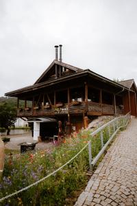 a large wooden building with a fence and flowers at Apartmán BeVi in Loučná nad Desnou