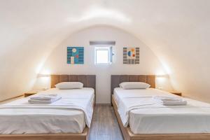 two beds in a room with an attic at Santorini Wave Loft 2 in Gjilek