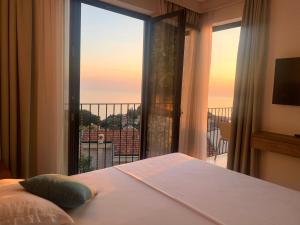 a bedroom with a bed and a large window with a view at REZEVICI BOUTIQUE VILLA in Petrovac na Moru