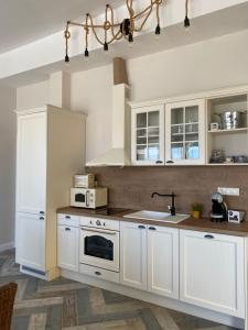 Una cocina con gabinetes blancos, un fregadero y un microondas. en Coastal home Arapya, en Tsarevo