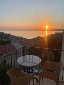 a sunset on a balcony with a table and chairs at REZEVICI BOUTIQUE VILLA in Petrovac na Moru