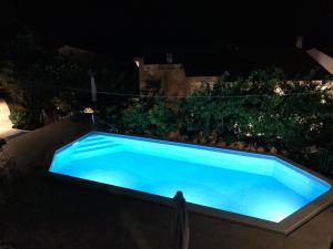 a large blue swimming pool in a yard at night at REZEVICI BOUTIQUE VILLA in Petrovac na Moru