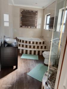 a bathroom with a tub and a toilet and a sink at Zuzani Ikhaya B&B in Grahamstown