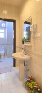 a bathroom with a sink and a toilet and a mirror at بيت عز اقامة راقية in Aţ Ţunḑubāwī