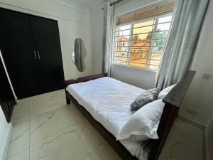 a small bedroom with a bed and a window at Creed Apartments in Kampala