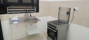 a small kitchen with a stove and a sink at رزات كاسا - للعائلات فقط in Gharnūt
