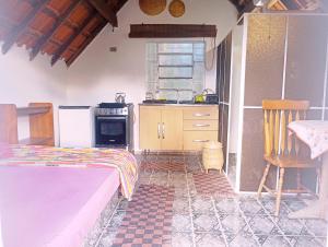 a bedroom with a bed and a kitchen with a stove at Chalé Rosa Chalezinho da Serra in Natividade da Serra