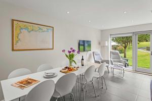 a white dining room with a white table and chairs at House 8 in Looe