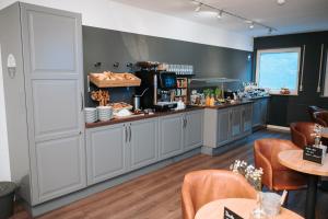 a restaurant with a counter and tables and chairs at Alpenglühen Smart Hotel in Olching